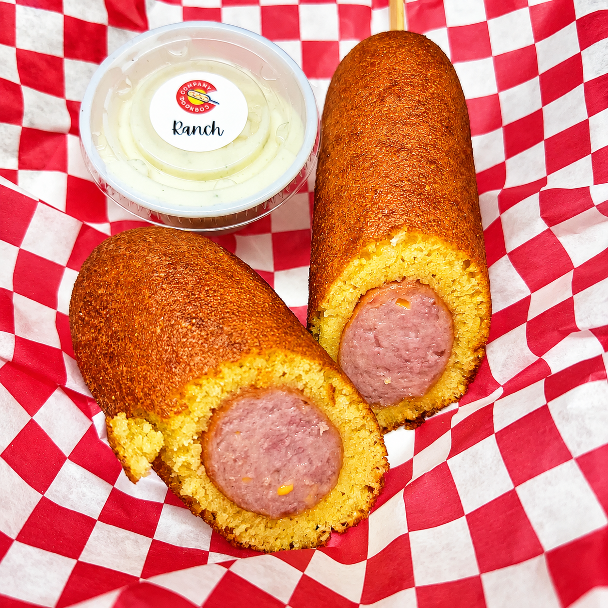 Cheddar corndog cut in half showing melted cheese, served with ranch